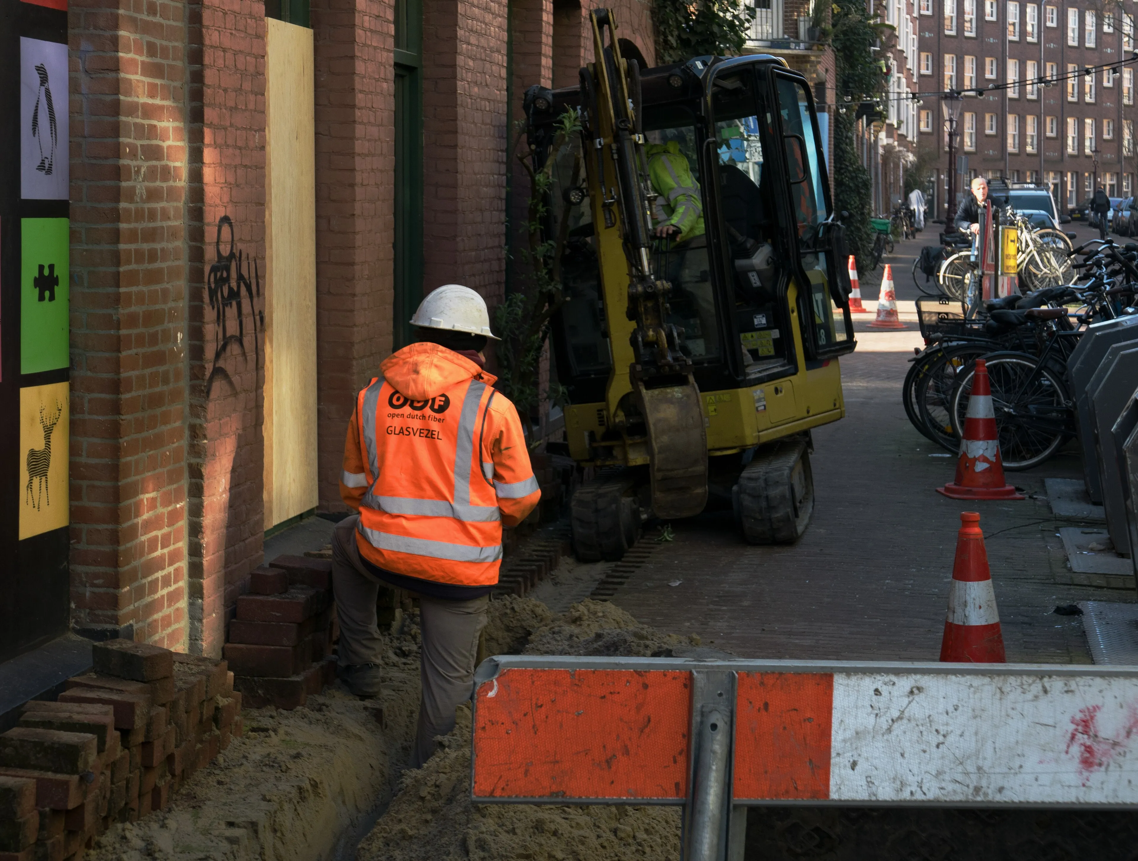 Worker laying fibre-optic cable in a footpath trench